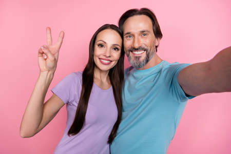 Photo of two partners make selfie hand fingers demonstrate v-sign isolated on pink color background