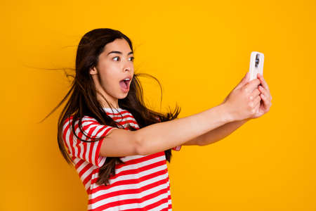 Photo of astonished positive lady hold use telephone make selfie open mouth isolated on yellow color backgroundの写真素材