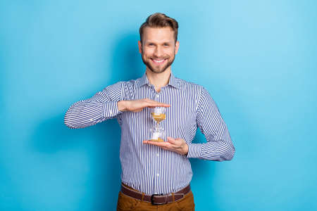 Photo of handsome man hold sanglass timer countdown till big sales on black friday isolated on blue...