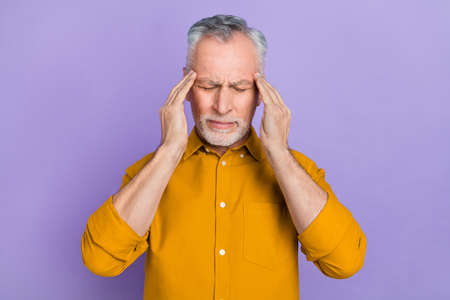 Photo of sad old grey hairdo man hands head wear mustard shirt isolated on violet color backgroundの写真素材