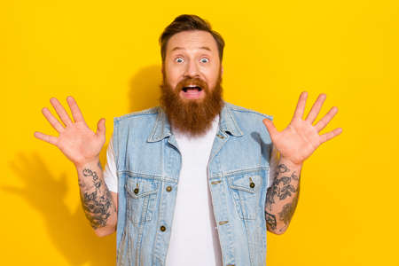 Portrait of astonished positive person raise opened arms stare speechless isolated on yellow color backgroundの写真素材