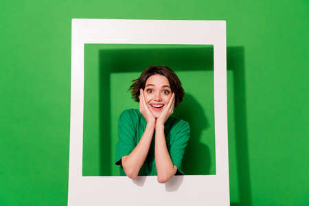 Photo of dreamy sweet lady wear spring outfit looking inside big white photo frame isolated green...