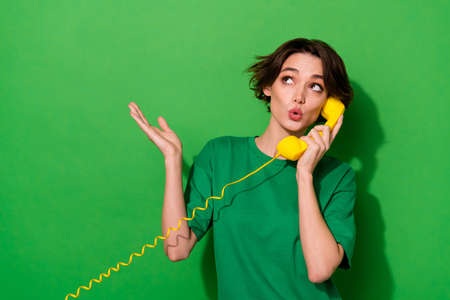 Photo of pretty dreamy lady wear spring outfit looking empty space talking phone isolated green color backgroundの写真素材
