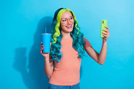 Photo of young good mood young blogger girl take selfie have online stream with subscribers isolated on blue color backgroundの写真素材