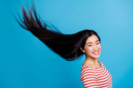 Photo of sweet pretty woman wear striped shirt air blowing hair flying smiling isolated blue color backgroundの写真素材