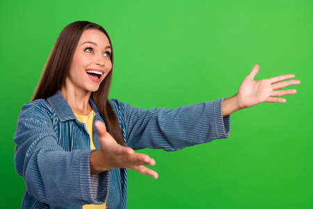 Profile photo of overjoyed cheerful girl look empty space arms wait catch isolated on green color backgroundの写真素材