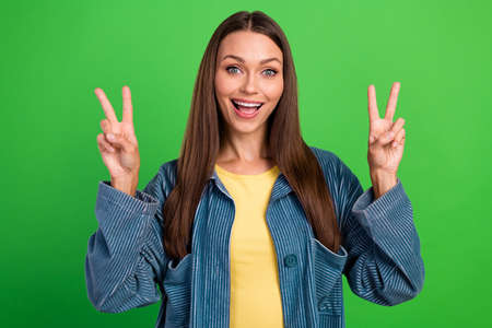 Photo of carefree overjoyed person arms fingers demonstrate v-sign isolated on green color...