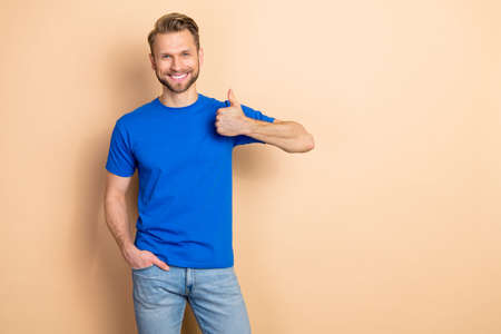 Photo of positive nice person arm finger demonstrate thumb up isolated on beige color background