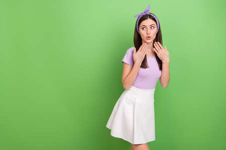 Photo of dreamy impressed lady dressed purple t-shirt hairband looking empty space isolated green color backgroundの写真素材