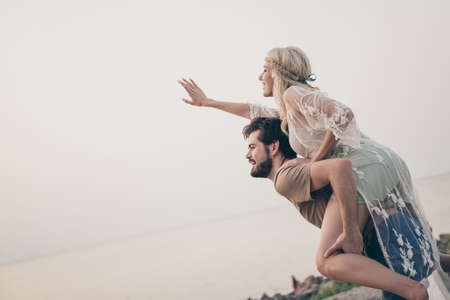 Photo of inspired honeymoon couple guy piggyback girlfriend wear boho outfit nature seaside beach outdoorsの写真素材
