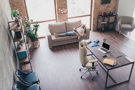 Photo of cute tired businesswoman wear blazer lying couch reading book indoors workplace workstation