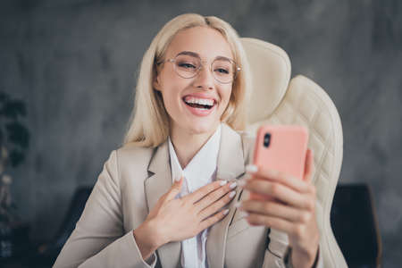 Photo of funny funky girl ceo formalwear video call modern gadget laughing indoors workplace...