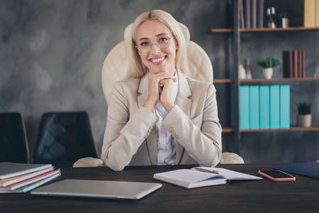 Portrait of cheerful charming person sitting chair toothy smile look camera workplace office indoorsの写真素材