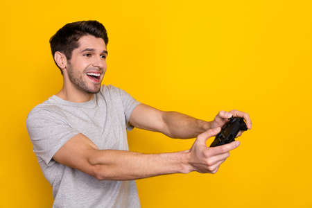 Photo of cute brunet young guy playstation look promo wear grey t-shirt isolated on yellow color...