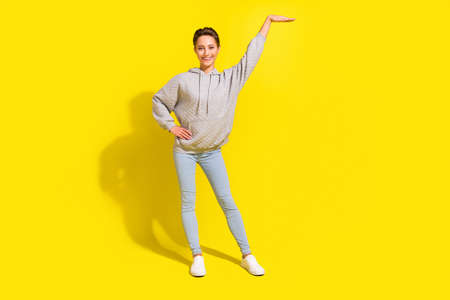 Full body photo of cool brown hair millennial lady measure wear sportcloth jeans sneakers isolated on yellow backgroundの写真素材