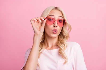 Photo of impressed young blond lady wear spectacles t-shirt isolated on pink color backgroundの写真素材