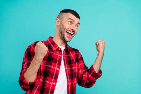 Photo of hooray millennial brunet guy hands fists wear checkered shirt isolated on teal color backgroundの写真素材