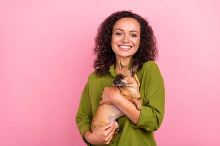 Photo of cheerful positive young afro american woman hold hands dog best friend isolated on pink color backgroundの写真素材