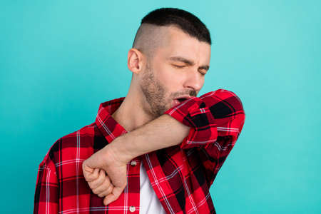 Photo of tired young brunet guy sneeze wear checkered shirt isolated on teal color backgroundの写真素材