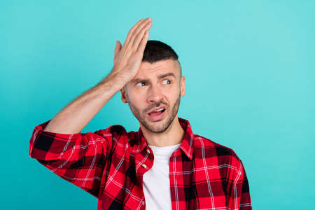 Photo of unhappy upset sad man hold hand head forget remembers mistake isolated on teal color backgroundの写真素材