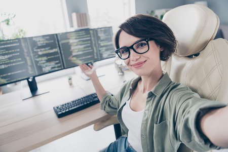 Self-portrait of attractive cheerful skilled experienced girl demonstrating code html network database at work place space indoorsの写真素材