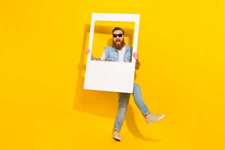 Full body photo of crazy carefree person hold paper album card isolated on yellow color backgroundの写真素材