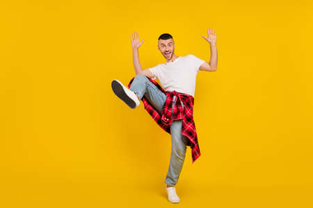 Full length body size photo man in casual clothes fooling overjoyed isolated vibrant yellow color backgroundの写真素材