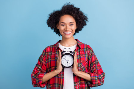 Photo of young black girl happy positive smile hold alarm clock timer schedule management isolated...