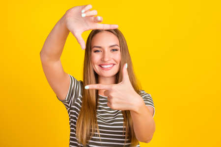 Photo of gorgeous cheerful girl toothy smile arms fingers show cadre gesture isolated on yellow color backgroundの写真素材