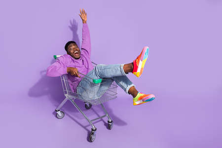 Full length body size view of attractive crazy cheery guy riding cart fooling isolated over vivid violet lilac color backgroundの写真素材