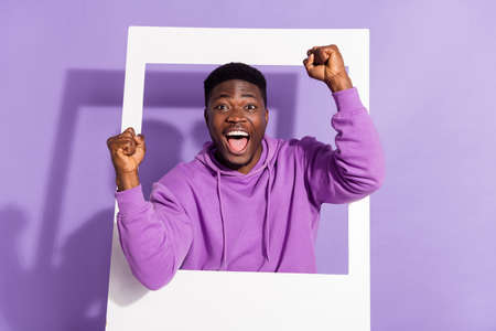 Photo of satisfied excited person raise fists celebrate achieve success isolated on purple color backgroundの写真素材