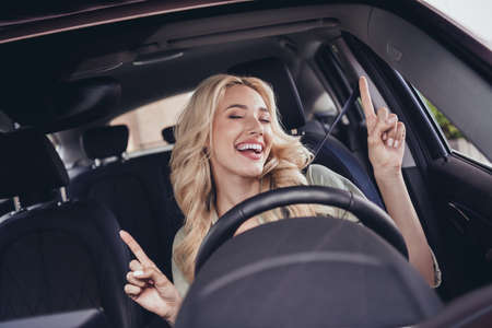 Photo of cheerful pretty lady sitting driver seat point fingers enjoy listen song have good moodの写真素材