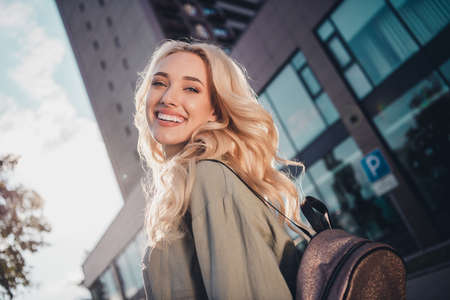 Profile side view portrait of attractive blond cheerful girl good mood strolling going to university study in town outdoorsの写真素材