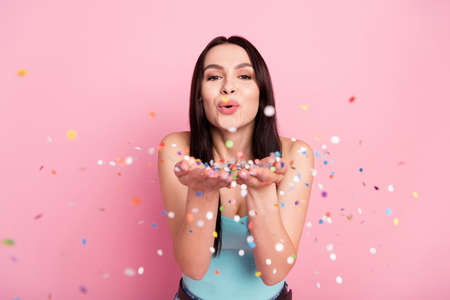 Photo of girlish millennial party lady blow confetti wear blue top isolated on pink color backgroundの写真素材