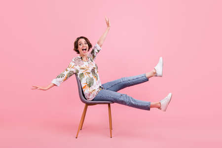 Full length body size photo woman sitting on chair laughing overjoyed isolated pastel pink color backgroundの写真素材