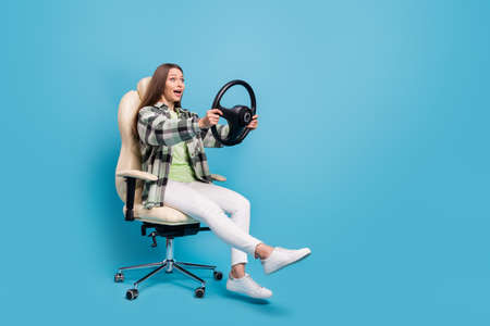 Full length profile side photo of young girl sit chair hold steering-wheel amazed shocked speed...