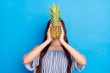 Photo of charming pretty lovely woman hold hands cover face pineapple isolated on blue color backgroundの写真素材