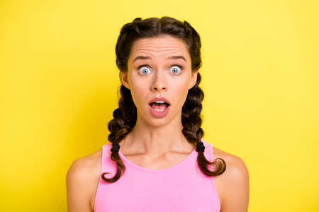 Photo of charming impressed young woman pigtails wear tank top big eyes open mouth isolated yellow color backgroundの写真素材