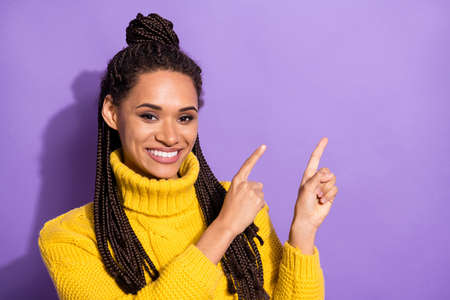 Photo of optimistic nice brunette girl point empty space wear yellow sweater isolated on purple...