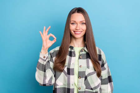 Photo of funny long hairdo young lady show okey sign wear grey shirt isolated on blue color...