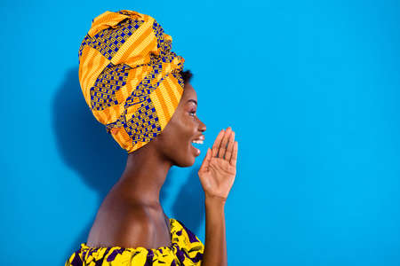 Profile portrait of attractive positive dark skin girl arm near open mouth look empty space isolated...