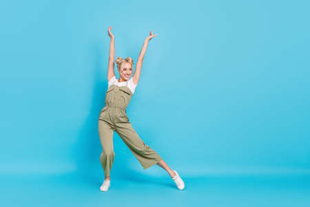 Full length photo of sweet blond lady dance wear t-shirt overall sneakers isolated on blue backgroundの写真素材