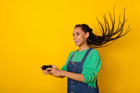 Portrait of attractive carefree person enjoy playing games flying hair isolated on yellow color...