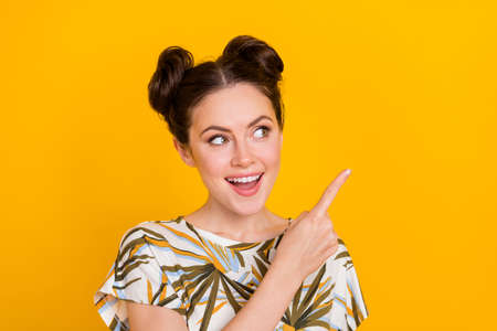 Photo of sweet dreamy lady dressed print t-shirt looking pointing empty space isolated yellow color background.の写真素材
