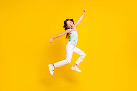Full size profile side photo of cheerful crazy little girl jump up air good mood isolated on bright yellow color backgroundの写真素材