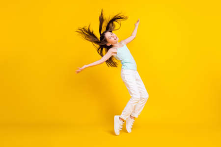 Full body profile side photo of active funky little girl fly hair good mood isolated on yellow color...