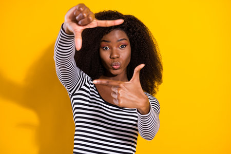 Photo portrait of young woman sending air kiss showing cadre border for camera isolated vibrant yellow color backgroundの写真素材