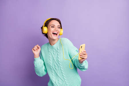 Portrait of attractive cheerful girl listening pop having fun dancing free time isolated over violet...