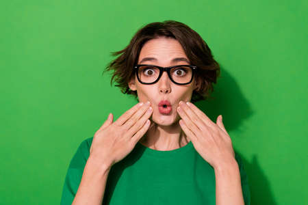 Photo of excited funky lady wear spring outfit spectacles big eye arms cheeks isolated green color backgroundの写真素材