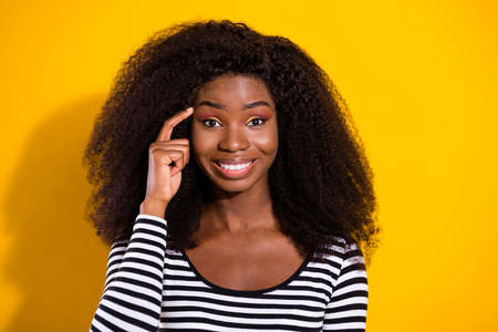 Photo portrait of young model keeping finger near forehead smiling isolated bright yellow color backgroundの写真素材